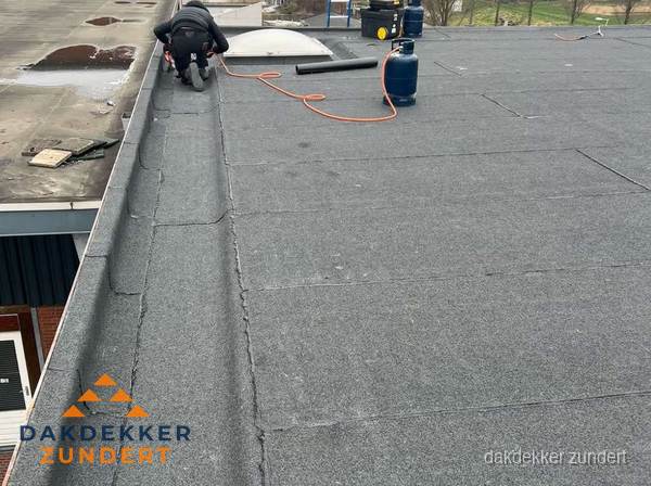 Dakdekker repareert bitumen dakbedekking op groot plat dak in Zundert