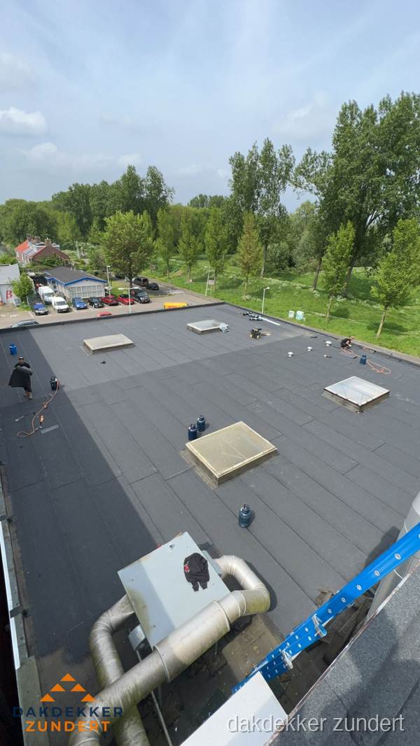 Dakdekker aan het werk op groot plat dak met bitumen in Zundert
